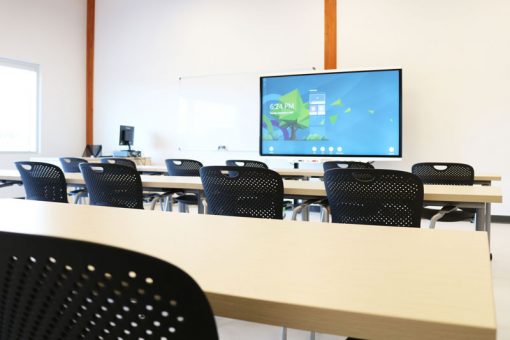 View of an SGEI classroom equipped with long tables, chairs and a Smart Board