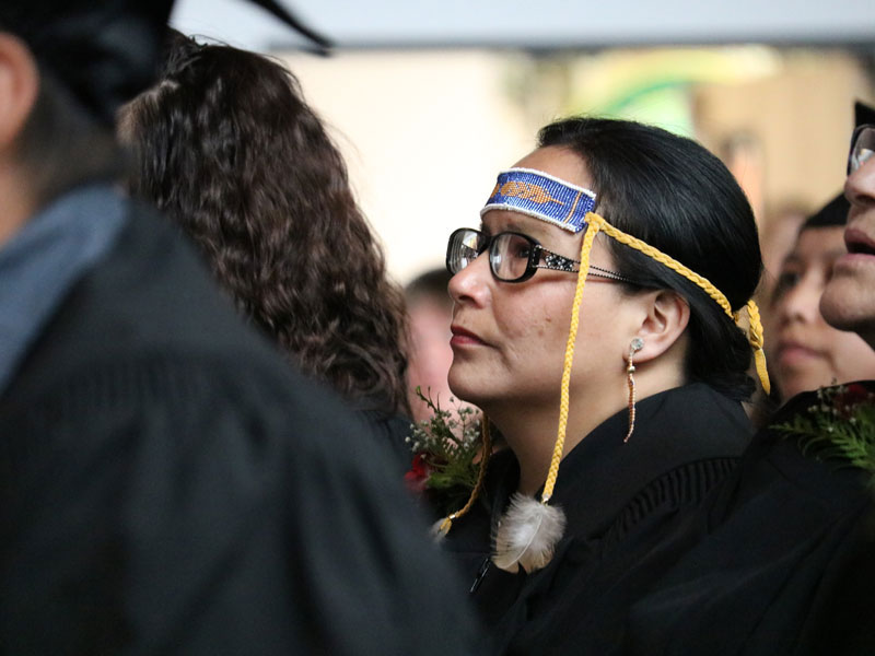 Anishinaabe woman sitting among fellow graduates