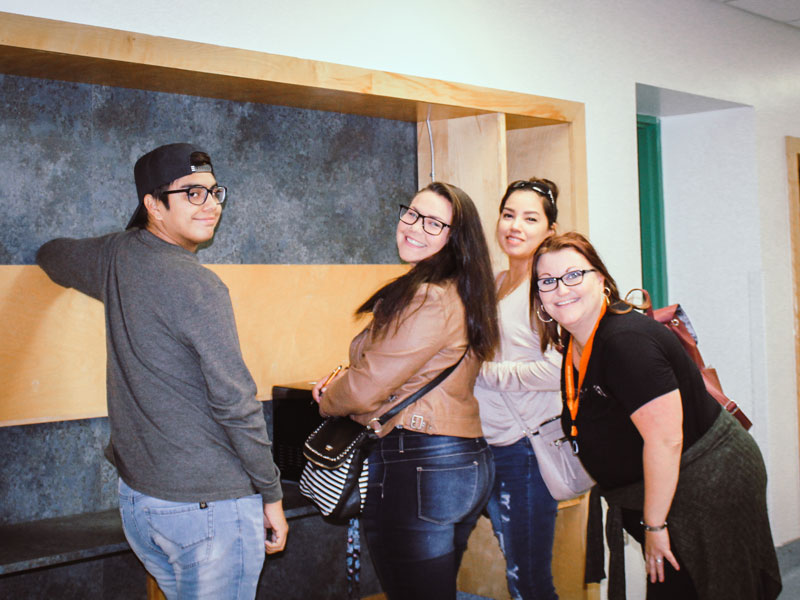 Four post-secondary students smiling in a hallway