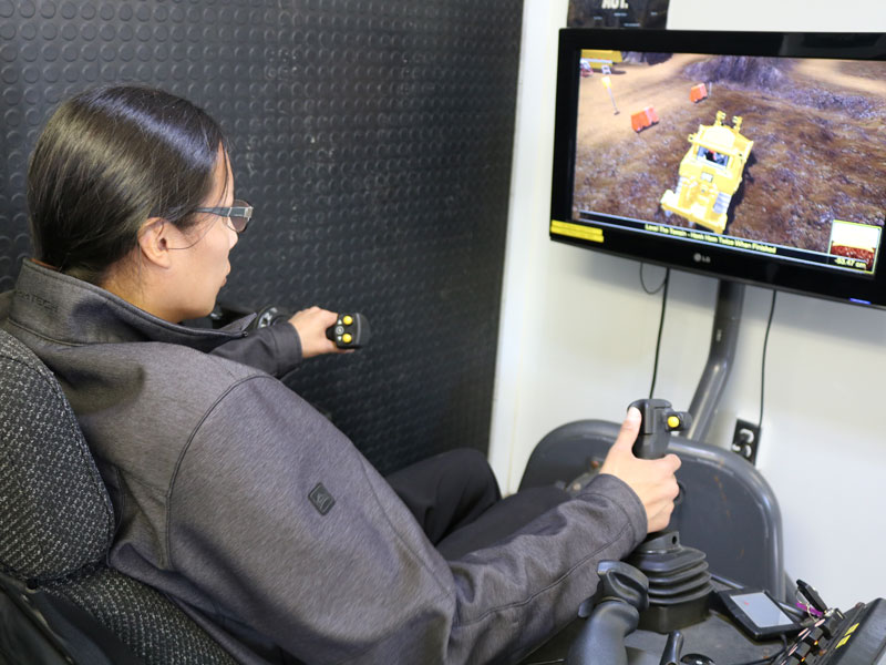 Young man sitting at a heavy equipment simulator using the controls