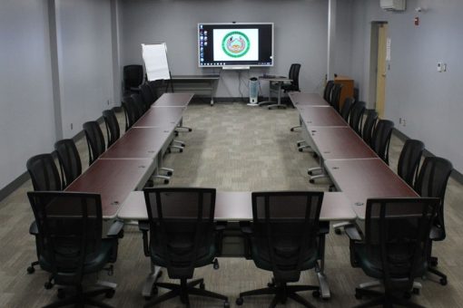 Classroom at our Kenora Campus featuring desks in a u-shape formation and roller chairs facing a Smart Board