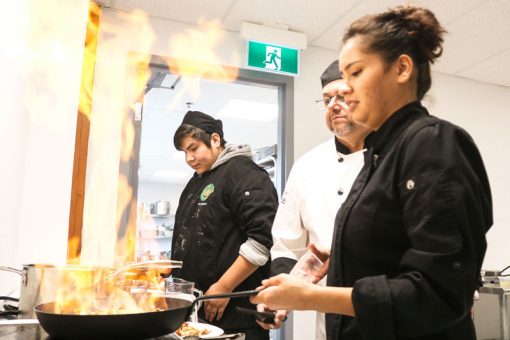 Kenora_CulinaryLab Female student flambéing food in SGEI's culinary lab