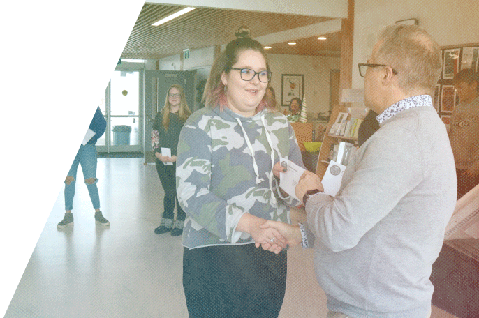 A female SGEI student receiving an envelope from a teacher