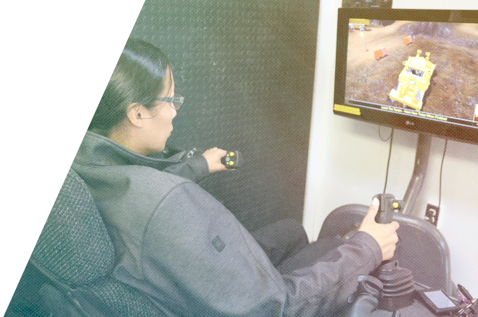 Man sitting at a heavy equipment simulator working on the controls