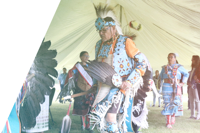 A powwow takes place underneath a tent