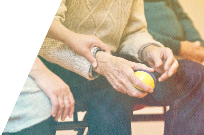 Elderly woman's hand holding a ball while a PSW touches her arm