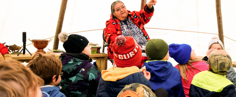 An elder from the community engaged in conversation with a group of children