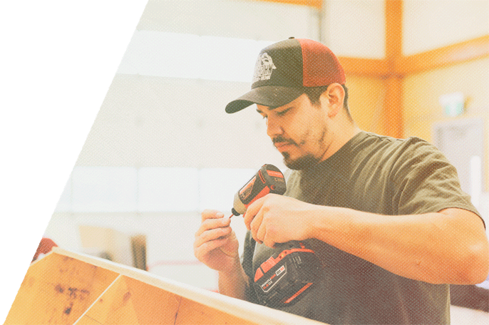 Male SGEI student fitting a bit onto a screwdriver in SGEI's Trades lab