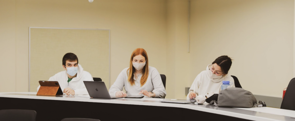 Three students in a telepresence room engaged in virtual learning