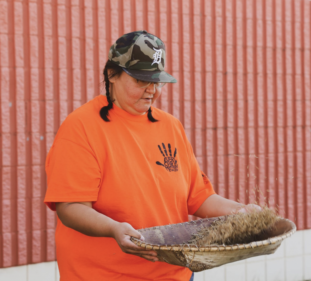 Anishinaabe woman winnowing wild rice