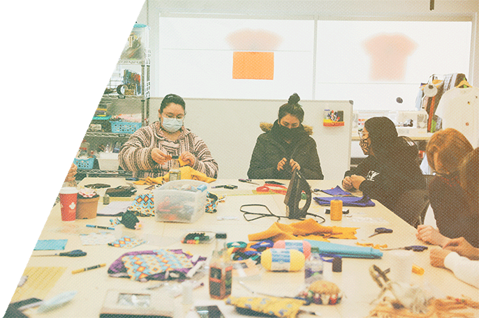 Group of four people sitting at a table doing crafts in SGEI's Makerspace