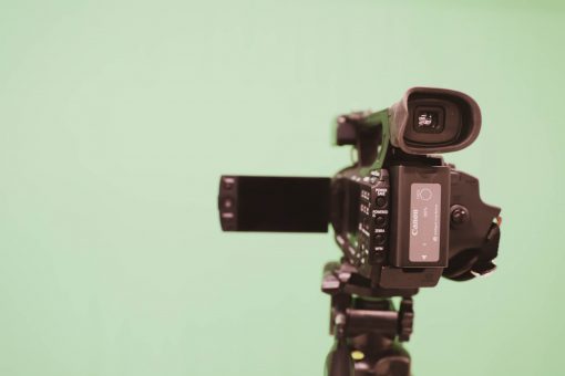 Video camera on a tripod pointing to a green screen