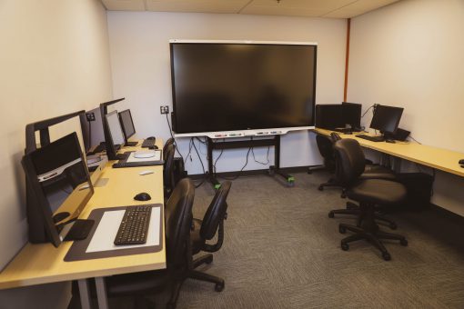 Interior of a computer lab equipped with five desktop computers and a Smart Board