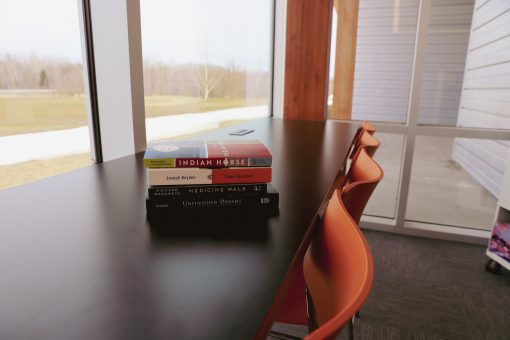 Stack of four novels on a long table facing a window