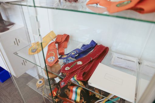 Set of colourful hand-beaded ties in a glass display case