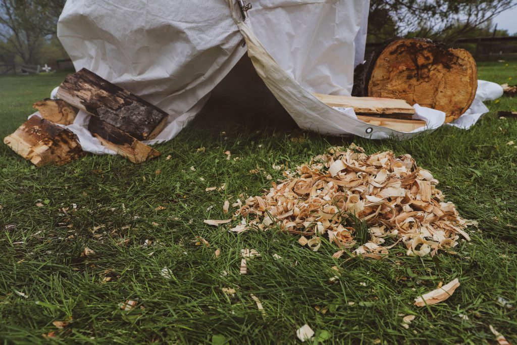 Entrance to a traditional smoke hut accompanied by pile of shavings and kindling