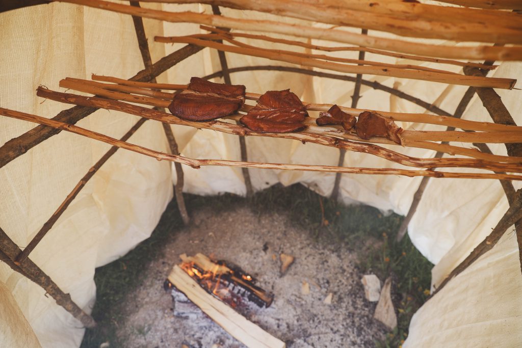 A traditional smoke hut scene featuring the smoking of fish