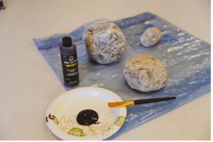 A group of rocks on a plastic sheet with black paint