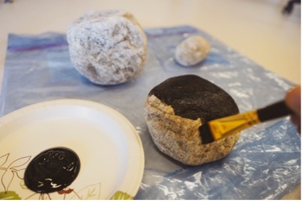 A rock being painted with black paint