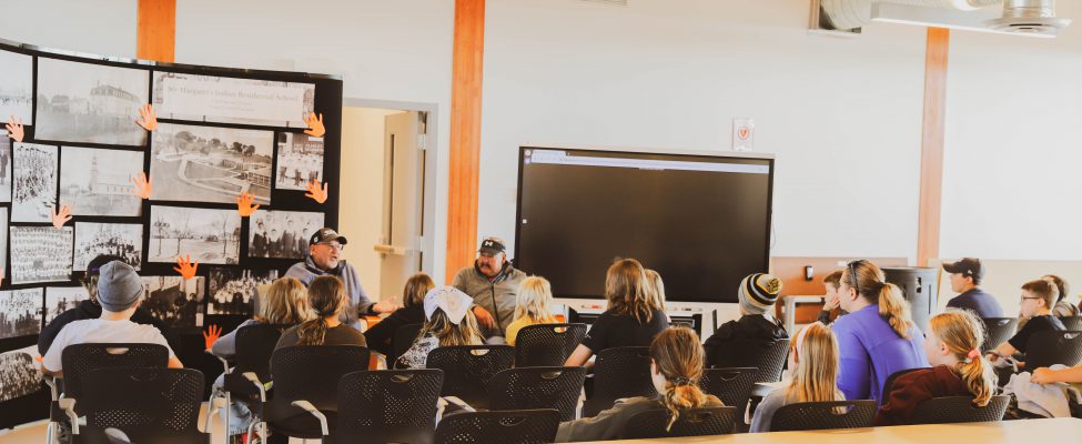 Two local elders share knowledge with a group of youth