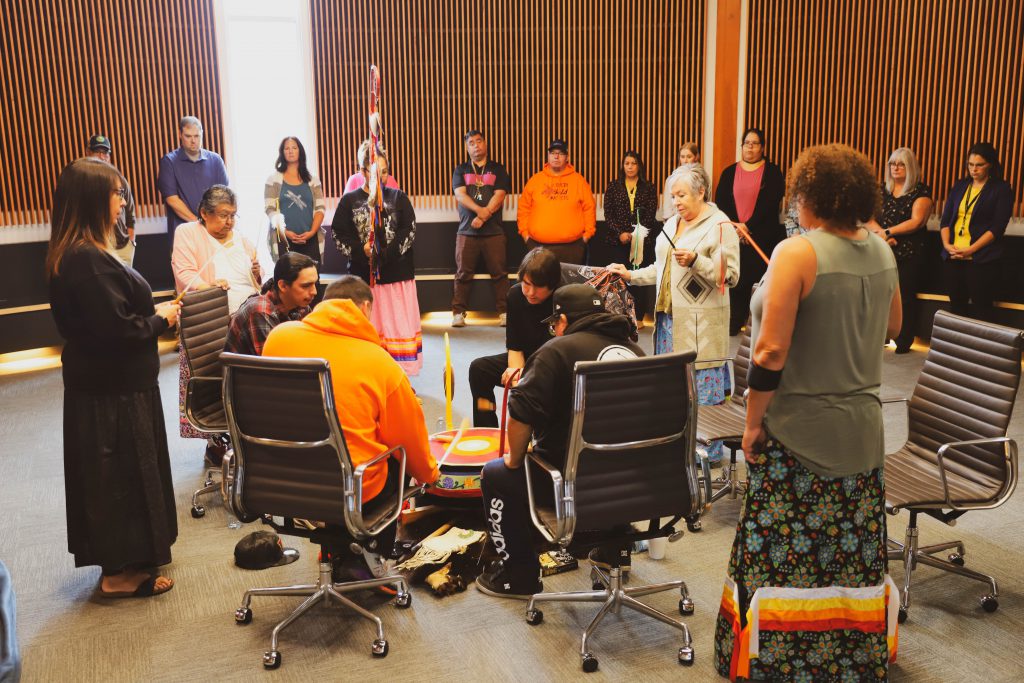 People gathered around a traditional Anishinaabe drum during a ceremony.