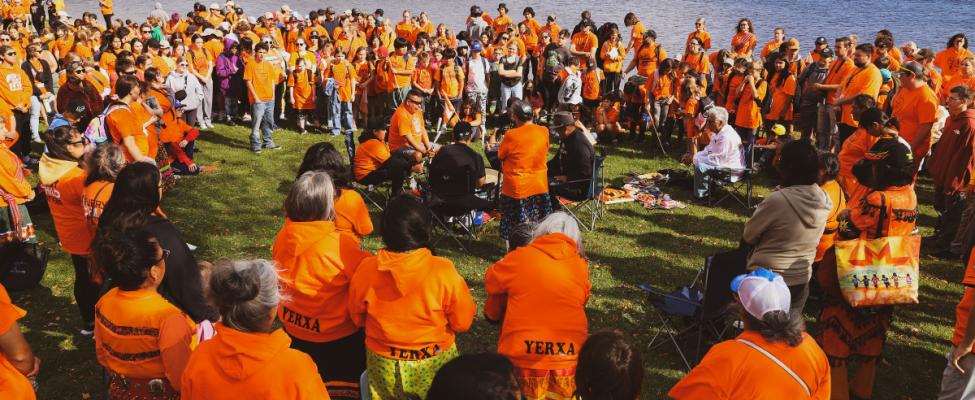 A group surrounds traditional drummers during Orange Shirt Day.