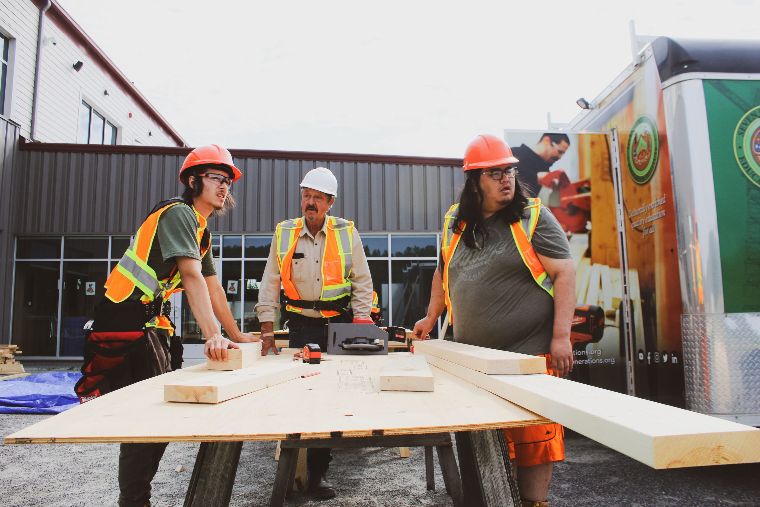 Three men standing at a wooden table on construction site