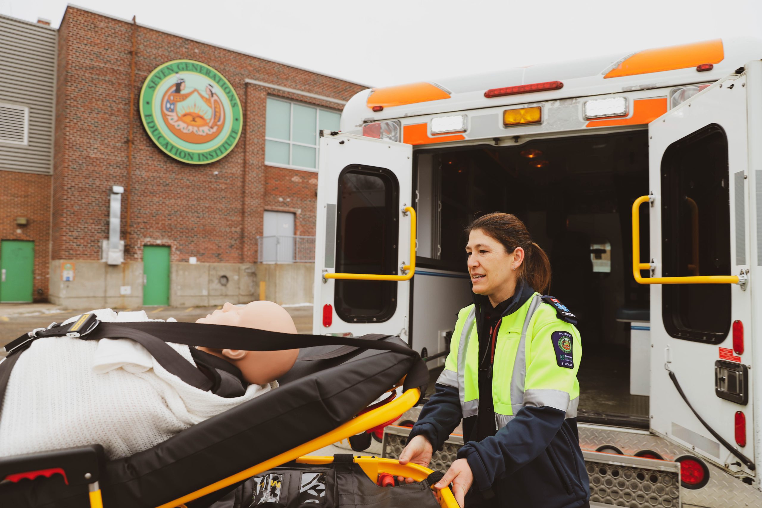Paramedic student wheeling a stretcher into the back of an ambulance
