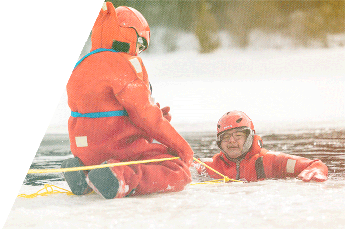 A person with a rope helping a man out of an icy river.