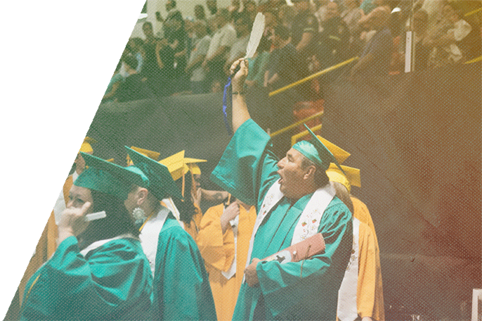 Anishinaabe man at SGEI graduation ceremony calling out and raising his arm holding a feather.