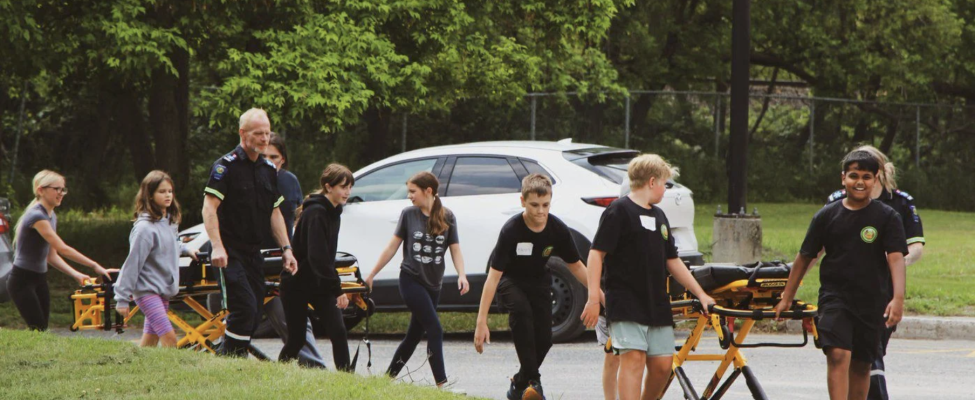 Group of youth walking outside with stretchers at SGEI's Explore Paramedicine Summer Camp.
