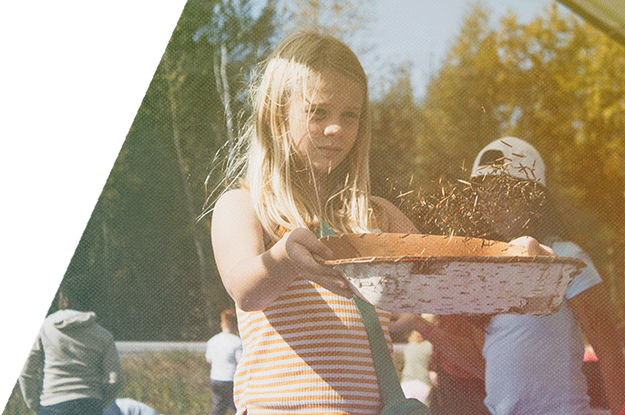 A student at Fall Harvest practices winnowing wild rice.